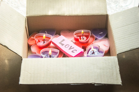 Lots of heart-shaped candles are in a Valentine's Day gift box with pink paper and love messages.の写真素材