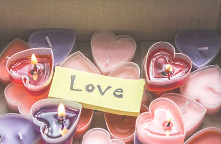 Lots of heart-shaped candles are in a Valentine's Day gift box with yellow paper and love messages.の写真素材