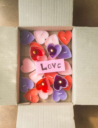 Lots of heart-shaped candles are in a Valentine's Day gift box with pink paper and love messages.の写真素材
