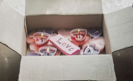 Lots of heart-shaped candles are in a Valentine's Day gift box with pink paper and love messages.の写真素材