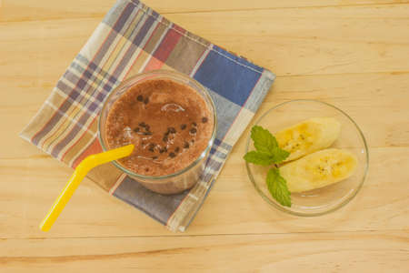 Chocolate Banana Shake Topping Sprinkled with Chocolate Chips, Banana and Mint Leaves with Straw on Clothの写真素材