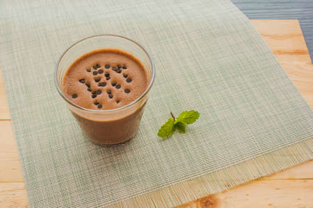 Chocolate banana smoothie topping sprinkled with chocolate chips banana slices on a wooden floor.の写真素材