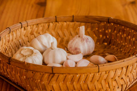 Dried garlic is placed in a wicker basket placed on a wooden floor.の写真素材