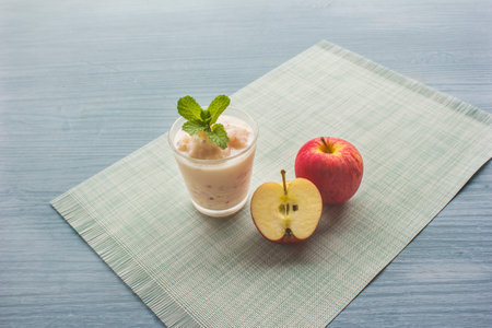 Apple smoothie with yogurt topped with mint leaves and halved apples placed on a clothの写真素材