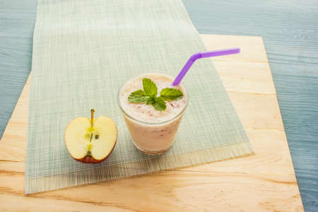 smoothie with yogurt topped with mint leaves and halved apples placed on a clothの写真素材