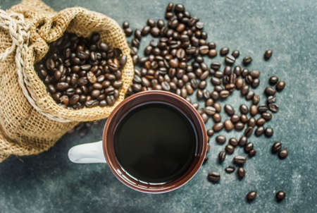 Cup of black coffee and bag of coffee beans on black backgroundの写真素材