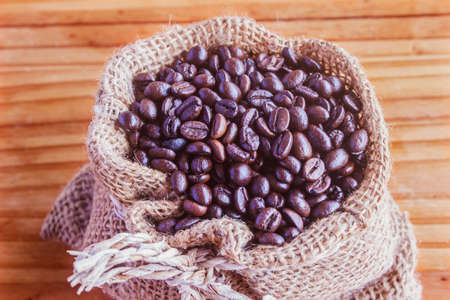 A bag of coffee beans on an old wooden floorの写真素材