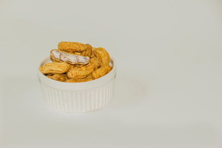 Boiled Peanuts In a white cup and boiled peanuts spread and open outside the bowl on a white background.の写真素材