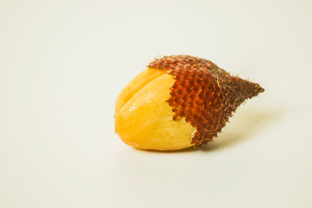 Snake fruit is a fruit that has a sweet and sour taste. Peel one fruit on a white background.の写真素材