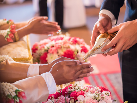 Thai wedding ceremony, water pouring from conch shell to bless the groom and the brideの写真素材