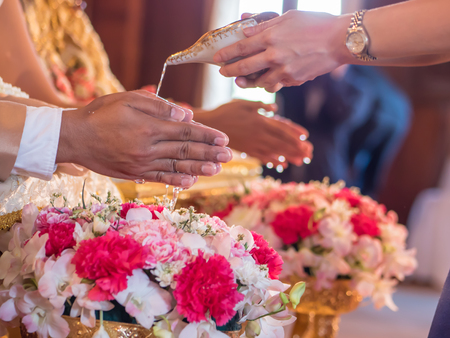 Thai wedding ceremony, water pouring from conch shell to bless the groom and the brideの写真素材