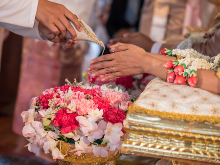 Thai wedding ceremony, water pouring from conch shell to bless the groom and the brideの写真素材