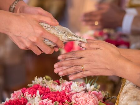 Thai wedding ceremony, water pouring from conch shell to bless the groom and the brideの写真素材