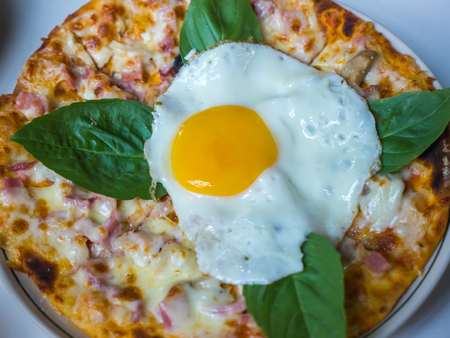 Bacon cheese pizza with basil and egg on top, Homemade pizzaの写真素材