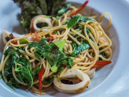 Spicy chili basil spaghtti with squid on plateの写真素材