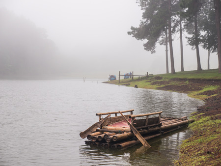 Wood raft on lake in mist with tourist tent in national parkの写真素材