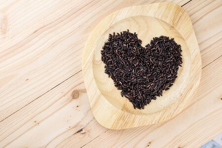 Close-up brown rice or riceberry organic food in bowl healthy on wood textureの写真素材