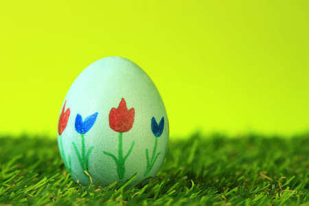 Easter decoration from single, colorful painted, Easter egg in green artificial grassの写真素材