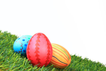 Colorful Easter eggs on artificial grass in front of white background