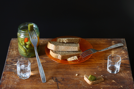 Feast for two. Vodka, black bread, salted cucumber on a wooden background. Binge and  appetizer in Russian style.の写真素材