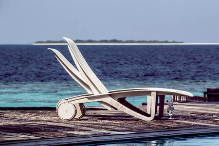 A seascape photo of two deckchairs and a glass by the sea   ocean in the Maldivesの写真素材