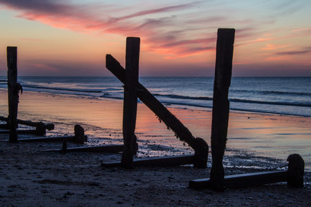 Sunset by the sea with a derelict sea wall near Sherringhamの写真素材