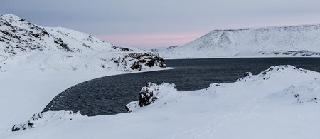 Panoramic photo of the Lake of Kleifarvatn, Reykjanes Peninsula, Iceland. The landscape is covered in snow and the sun is just coming up.の写真素材
