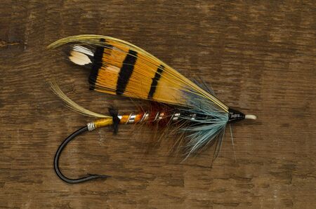 Traditionally dressed Durham Ranger salmon fly shot against a wooden backgroundの写真素材