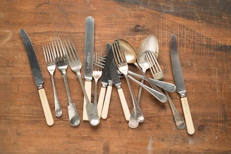 Variety of vintage cutlery layed out on wooden table.の写真素材