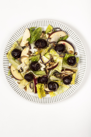 Beetroot and apple salad with lettuce, cumin seed and red onion on a white plate on white tableclothの写真素材