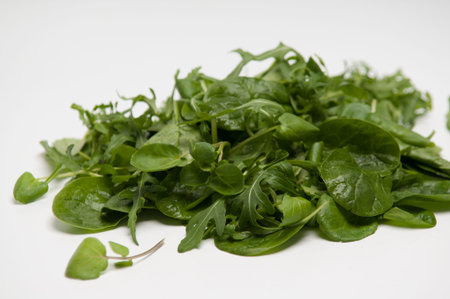 Pile of rocket and spinach mixed salad leaves isolated on whiteの写真素材