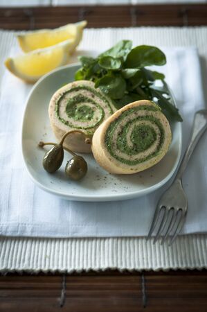 Salmon roulade on a white plate with capers and salad leavesの写真素材
