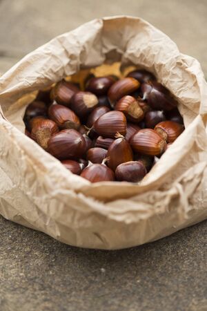 Uncooked chestnuts in a brown paper bagの写真素材