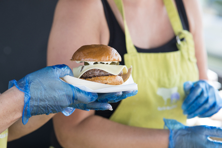 Gourmet cheeseburger being served to customer at an outside food stallの写真素材