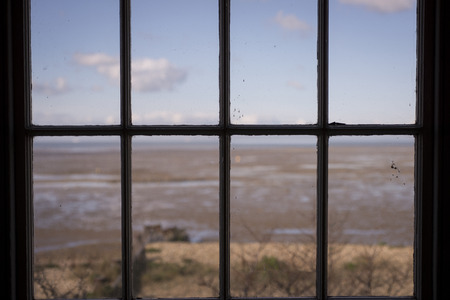 Looking through a sash window with a beach beyondの写真素材