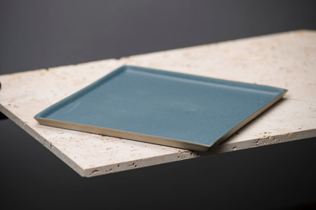 An empty blue square dining plate or tray on a stone countertop.