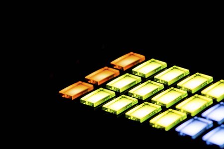 Array of lit buttons on a DJ console shot in the darkの写真素材