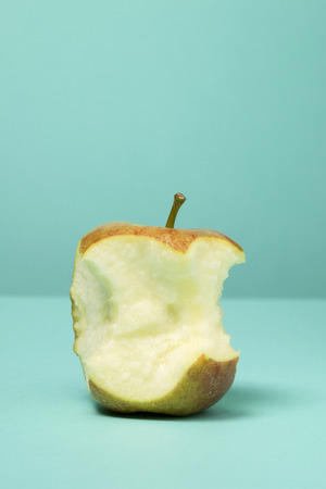 A part eaten apple on a blue green backgroundの写真素材
