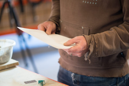 A piece of paper held by a person in brown sleeved shirt