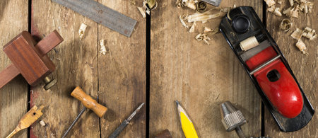 Old woodworking tools shot in website banner format. Tools include a bradle, punch, gauge, ruler,...