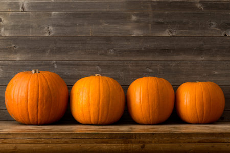Pumpkins of different sizes on a wooden shelf with copy space