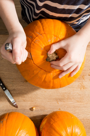 Overhead shot of hands using a knife to carve out the crown of a pumpkinの写真素材