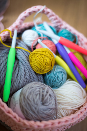 Balls of wool and crochet needles in a knitted woolen basketの写真素材