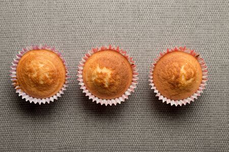 Overhead shot of three cupcakes with no frosting on a gray surfaceの写真素材