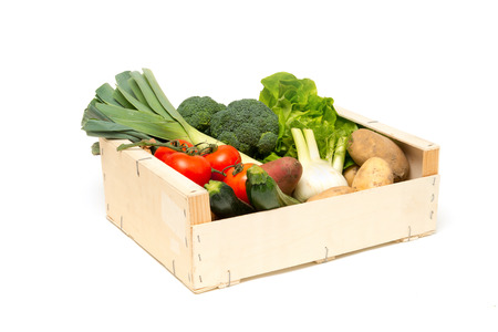 Wooden crate filled with a variety of fresh, ripe, farm-grown vegetables including leeks, broccoli, lettuce, tomatoes, sweet potatoes, zucchini, fennel, potatoes, and onions cut-outの写真素材