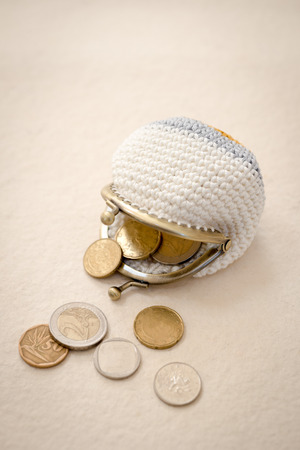 Coins spilling from a crocheted coin purseの写真素材