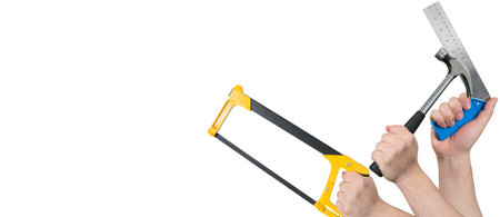 Hands holding a hacksaw, a hammer, and a steel L-shaped ruler with copy spaceの写真素材