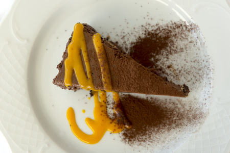 Overhead close up shot of a slice of chocolate cake drizzled with an orange syrup on a plateの写真素材