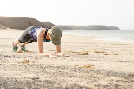 Woman doing fitness planking by the seasideの写真素材
