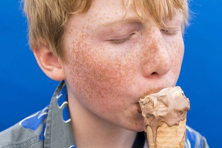 Young boy with eyes closed eating ice cream on a coneの写真素材